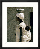 A Xhosa woman balances a container on her head and a baby on her back