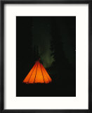 The glow from a campfire makes a shadow on a tepee