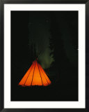 The glow from a campfire makes a shadow on a tepee