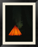 The glow from a campfire makes a shadow on a tepee