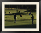 Two People Play Golf While Elk Graze on the Golf Course