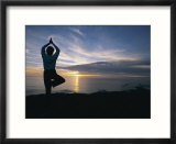 A woman practices yoga on the beach at sunset