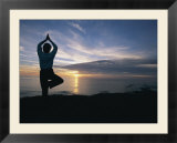 A woman practices yoga on the beach at sunset