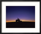 Silhouette of worker cutting grass at sunrise