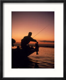 Silhouette of bass fisher at sunset