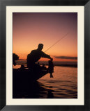 Silhouette of bass fisher at sunset