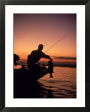 Silhouette of bass fisher at sunset