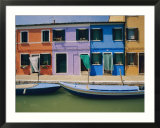 A view of the brightly colored buildings of Burano with gondolas floating at their doorsteps