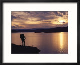 A hiker pauses for reflection alongside Lake Powell at sunset