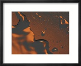 Close-up of Illuminated Orange Water Droplets and a Puddle on a Shiny Surface