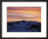 Sunset sky over snowy hills cast in shadow