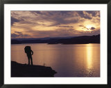 A hiker pauses for reflection alongside Lake Powell at sunset