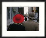 Rear view of two people wearing hats stopped at a crosswalk