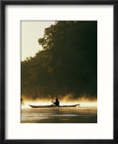 A kayaker paddles through the mist in the low sunlight