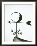 A Man-In-The-Moon Weather Vane on a Roof Top