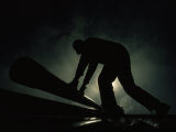 Silhouetted Oil Rig Worker Lifting a Pipe  Wyoming