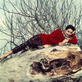 Young Woman Smiling and Lying on a Large Trunk on the Ground