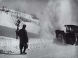 Man with His Back to the Camera on a Snow-Covered Street Watching a Snow Plow in Operation