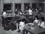 Two Girls Sitting at a Table are Playing Draughts  Four Young Woman are Playing Ping-Pong