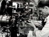 Close-up of a Young Worker Stitching a Shoe with the Aid of a Piece of Machinery