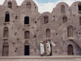 Two Figures Standing before the Ksar Ezzahara  an Example of Ghorfa Architecture  Ghorfas  Tunisia