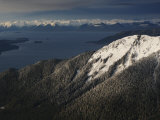 The sun breaks through the clouds  illuminating a peak near Hoonah