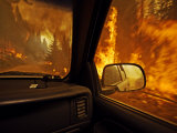 A firefighter supervisor drives through flames that jumped the road