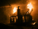 Flames engulf a house during a forest fire