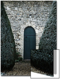 Stone Entry and Wood Door Flanked by Manicured Bushes