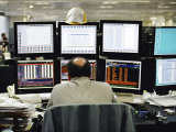 Balding Businessman Working at His Desk in Front of 6 Computer Monitors