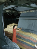 Woman Inspects Wool Blanket Material as it Piles Up under Rollers