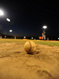 Baseball on a Dirt Mound During a Night Game