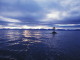 Man Standing on a Rock Surrounded by Water and Dramatic Sky