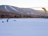 Man Tows Two Young Boys Behind a Kite across a Frozen Lake