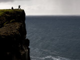 Two People Atop One of Iceland's Tall Coastal Cliffs