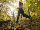 Woman Runs Through the Woods While Exercising in Early Fall