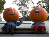 Painted Pumpkin Figures Wave from the Roof of a Roadside Stand