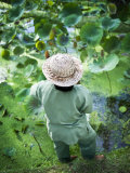 Person Wearing a Straw Hat Standing Near a Pond of Water Lilies