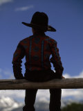 Rear View of a Boy in a Cowboy Hat Sitting on a Post