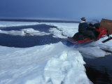 Man on a Snowmobile Jumping an Water-Filled Crack in the Ice