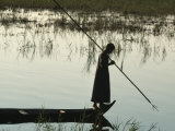 Woman Stands at the End of a Rowboat with a Fishing Spear