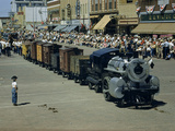 People Watch a Miniature Train Parade on Main Street