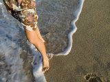 Frothy Waves Lap Up Against a Woman's Bare Feet