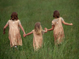 Three Young Girls in Matching Dresses  Hold Hands While Walking