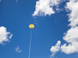 Yellow Smiley Face Parasail in Blue Skies with Nice Puffy Clouds