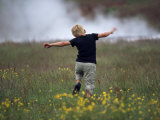 Boy Runs Through a Field of Grass and Yellow Flowers