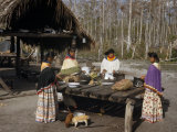 Women Standing at a Table in a Camp Clearing Prepare Dinner
