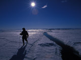 Hunter Walking across Arctic Ice with the Sun Bright in the Sky Behind