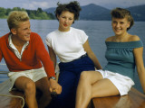 Man and Two Young Women Sit in the Stern of a Small Sailboat