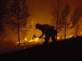 Firefighter Silhouetted on Hill Battling a Forest Fire at Night